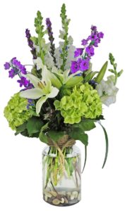 Sweet scented Casablanca lilies surrounded by green hydrangeas and additional wildflowers in a decorative modern vase with rope handle.