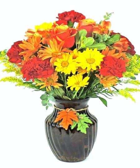 Gorgeous collection of fall flowers in dark vase with wooden leaf toggles, includes roses, carnations, daisies and alstromeria. ** out of town vase may vary **